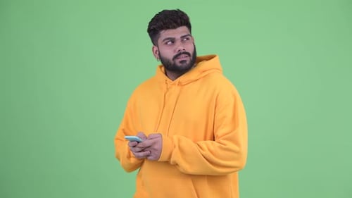 Young Adult Using Smartphone in Front of Green Screen