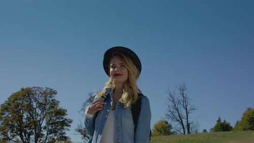 Smiling Woman with Hat Enjoys Sunny Mountain View