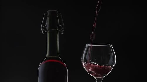 Rose Wine. Red Wine Pour in Wine Glass Over Black Background. Slow Motion