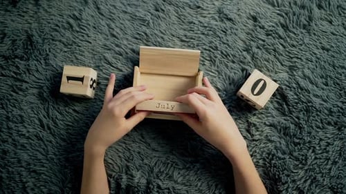 Child Arranges Wooden Block Calendar for July 4th