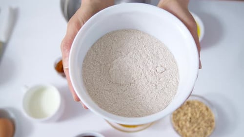 Whole grain flour in the hands of a woman cook. Close-up. 4K.