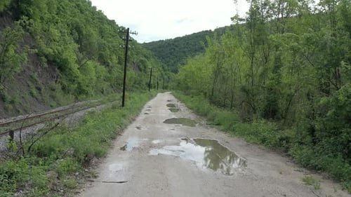 Puddles on rural road and railway track under hill 4K drone video