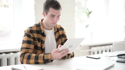 Young Adult Celebrates with Tablet at Desk
