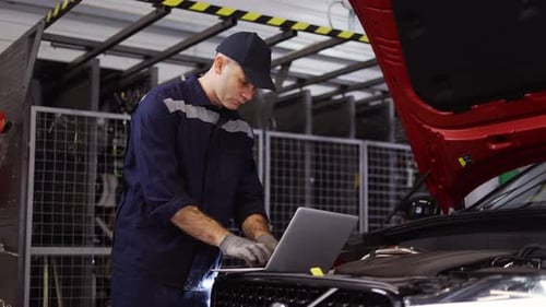 Auto Mechanic Uses a Laptop While Conducting Diagnostics Test