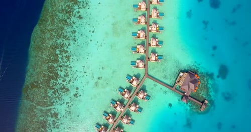 Aerial drone view of scenic tropical island and resort hotel with overwater bungalows in Maldives