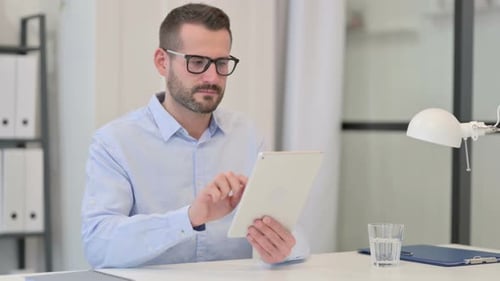 Middle Aged Man Using Tablet at Work
