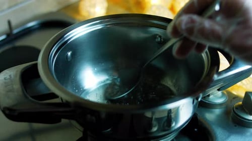 Person Stirring Liquid in Pot on Stovetop