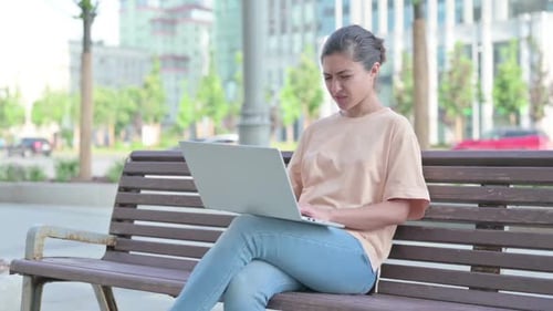 Woman Uses Laptop on Park Bench, Headache