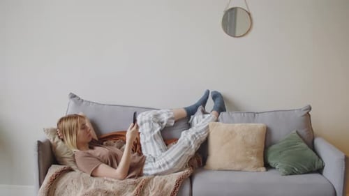 Woman Relaxes on Couch with Mobile Phone
