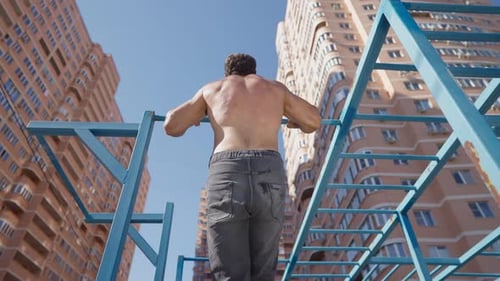Athletic Man with Naked Torso Pulls Up on Horizontal Bar on Bright Sunny Day
