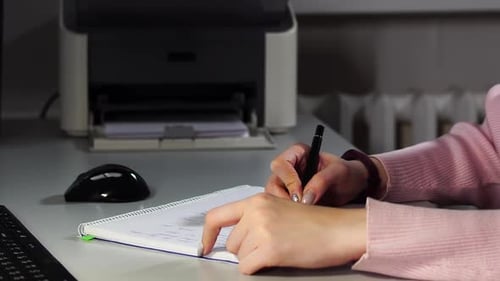 Nahaufnahme der Hände einer Studentin, die mit einem Stift in einem Copybook schreibt