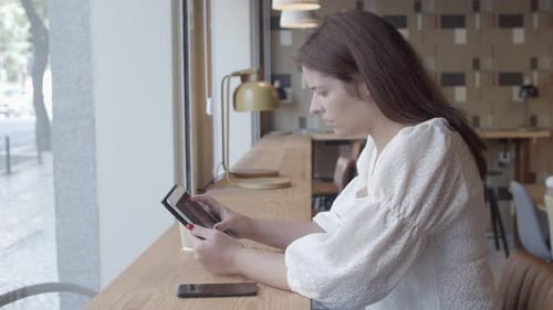 Woman Uses Tablet at Cafe Counter