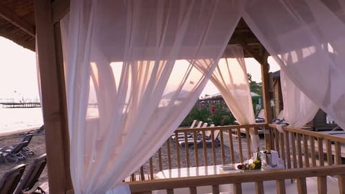 Sheds with Fabric White Curtains on the Beach in the Evening.