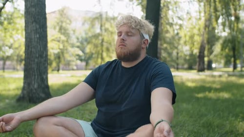 Obese Man Practicing Yoga Meditation in Park