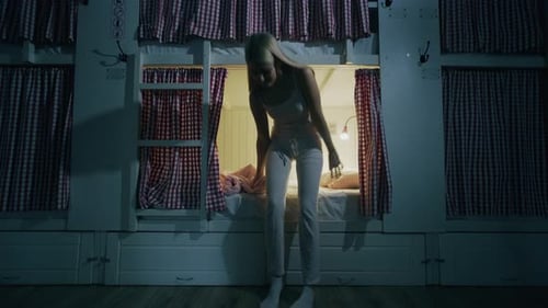 Young Girl Lays Down in Bed and Falls Asleep in Cozy Hostel Room