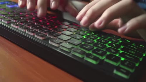 A Man Types Text on a Backlit Keyboard