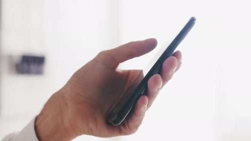 Slow-motion Close Up of a Young Man Hands Using a Smartphone Phone in a Home or Office