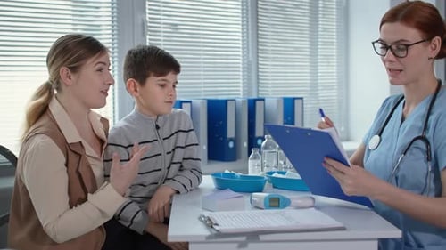 Doctor Talking to Mom and Little Boy at the Appointment at Hospital Cute Doctor in Glasses and Blue
