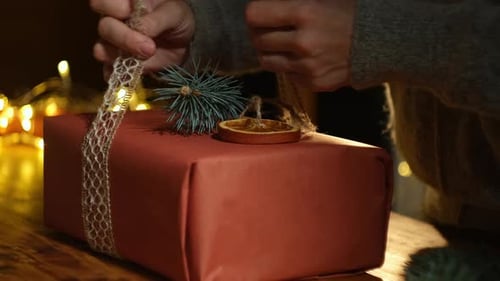 Hands Tying Festive Ribbon on Christmas Present