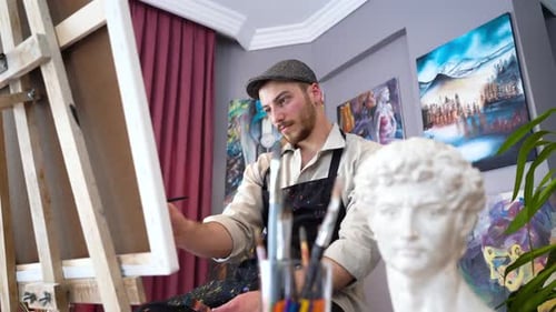 Young Adult Artist Painting on Canvas in Studio