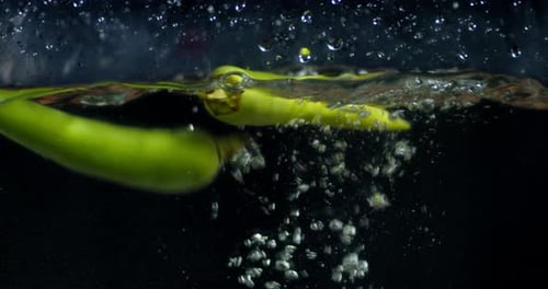 Green Pepper Falling in Water with Air Bubbles.
