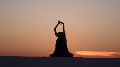 Elegant Woman Belly Dancing at Sunset in Desert