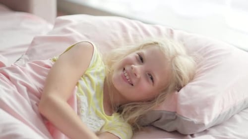 Smiling Young Girl Lying in Bed in Morning