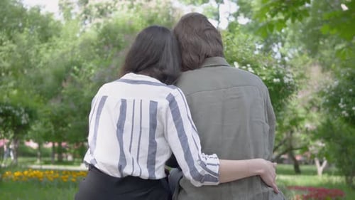 Back View of a Young Pretty Couple in Casual Clothes Spending Time Together in the Park, Having a