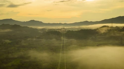 Transmission Towers Over Misty Hills at Sunset