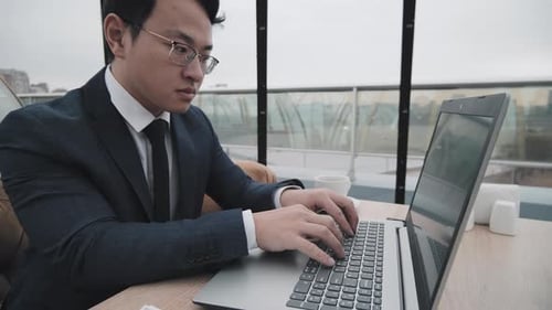 Asian Man Working in Rooftop Cafe