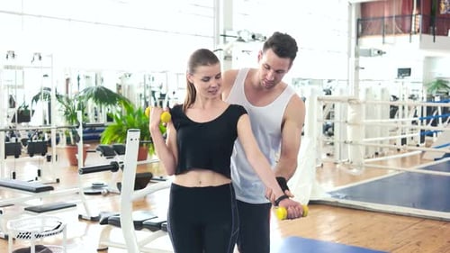 Woman Training with Dumbbells at the Gym