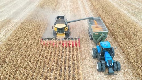 Foto aérea de una cosechadora cargando granos de maíz en un remolque de tractor. Máquinas agrícolas en funcionamiento