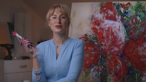 Woman Painter Holding Brush in Front of Painting