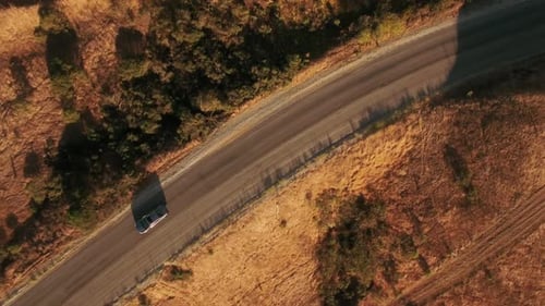 Car Drives on Country Road Surrounded by Golden Fields