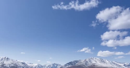 Timelapse of Sun Movement on Crystal Clear Sky with Clouds Over Snow Mountain Top