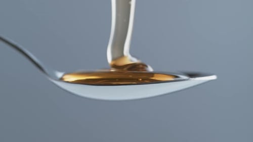 Thick honey dripping in spoon. Slow Motion.