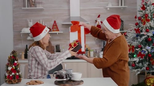 Women Exchanging Christmas Presents in Festive Kitchen