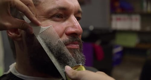 Man Getting Beard Shaped by Barber in Salon