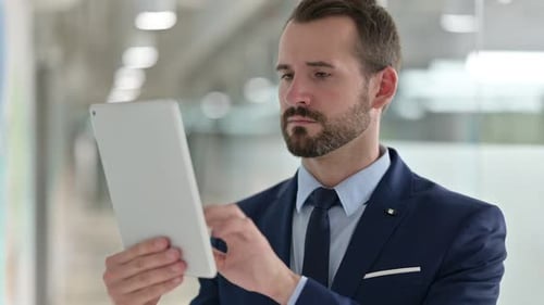 Bearded Man Using Tablet in Modern Office