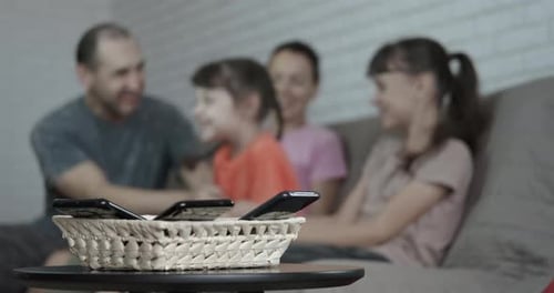 Family Laughing Together with Phones in Basket