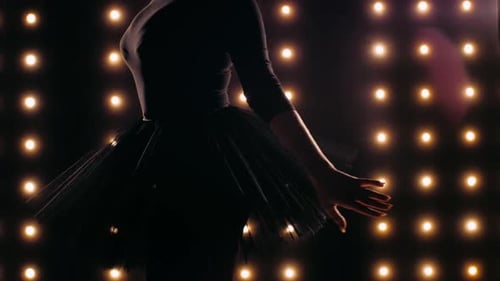 Silhouette of Ballerina in Black Dress Is Dancing Ballet in the Dark Studio