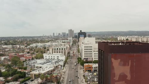 AERIAL: Flight Over Wilshire Boulevard Close To Street and Buildings with Car Traffic in Los Angeles