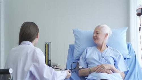 Doctor Checks Senior Woman's Blood Pressure in Hospital