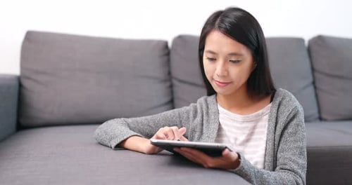 Woman Using Tablet Device on Gray Sofa