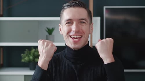 Excited Young Man Cheering and Gesturing Indoors