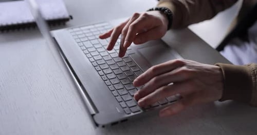 Hands Typing on Laptop Keyboard at Desk