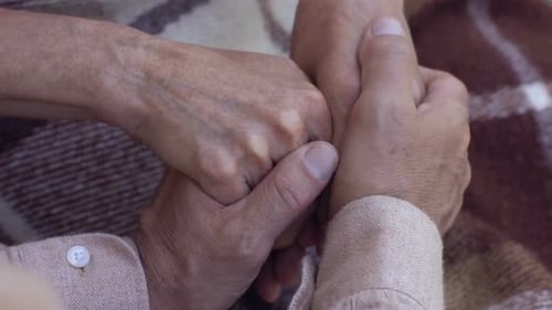 Alter Mann nimmt vorsichtig die Hände der Frau, Fürsorge und Zärtlichkeit in einer Beziehung