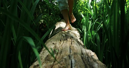 Woman walking over a wooden log in the park 4k