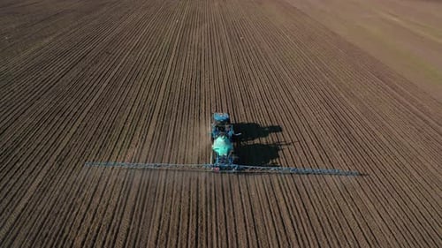 Vista aérea de un tractor que irriga un campo agrícola