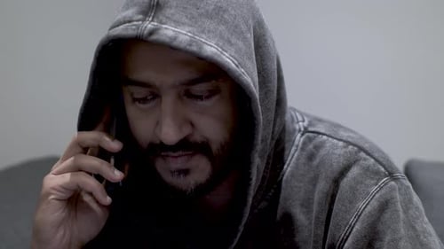 Close up shot of an Indian man talking to an anonymous caller, discussing the availability and negot